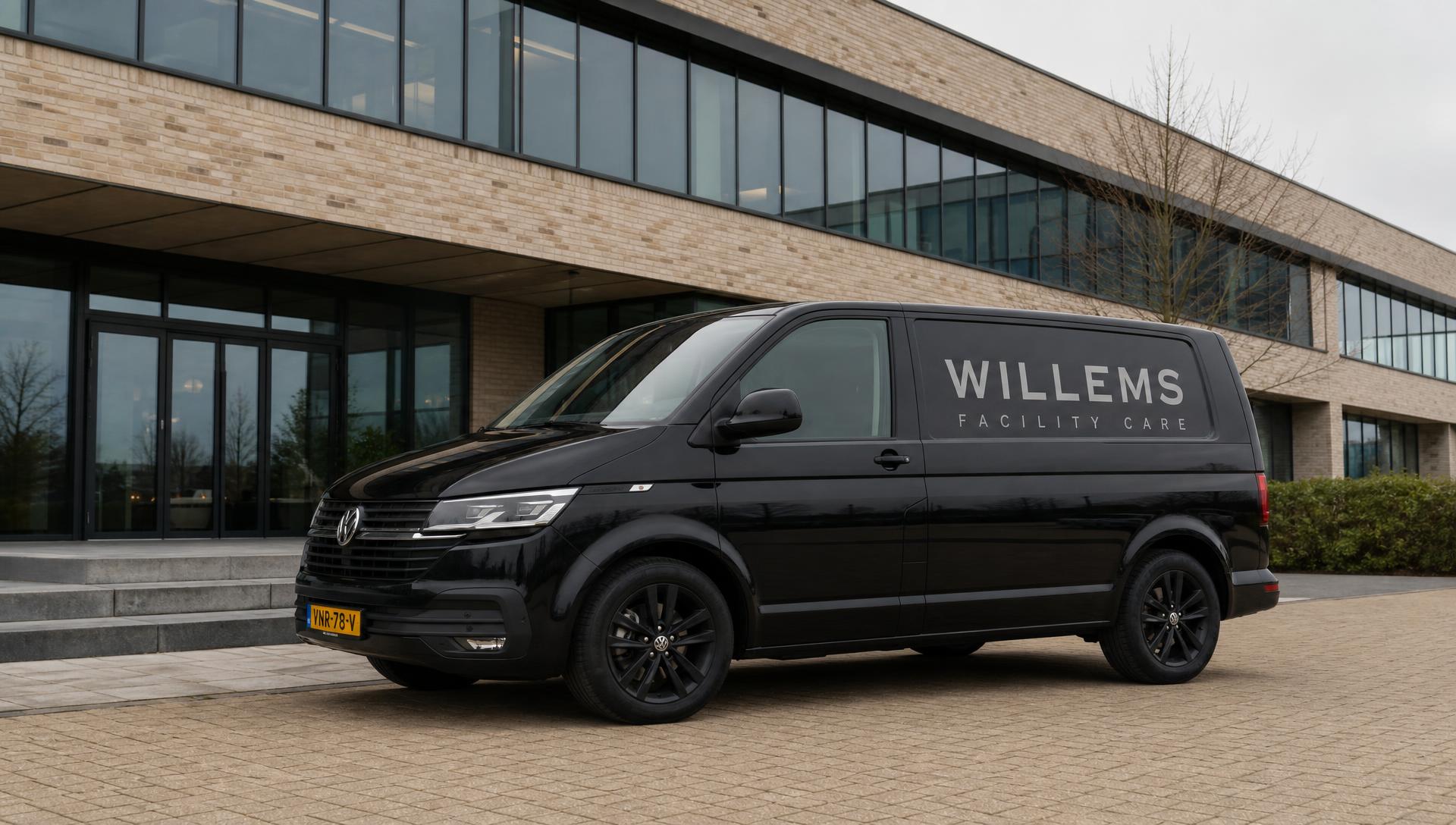 Zwarte Volkswagen Transporter van Willems Facility Care met zilveren belettering voor een modern bedrijfspand